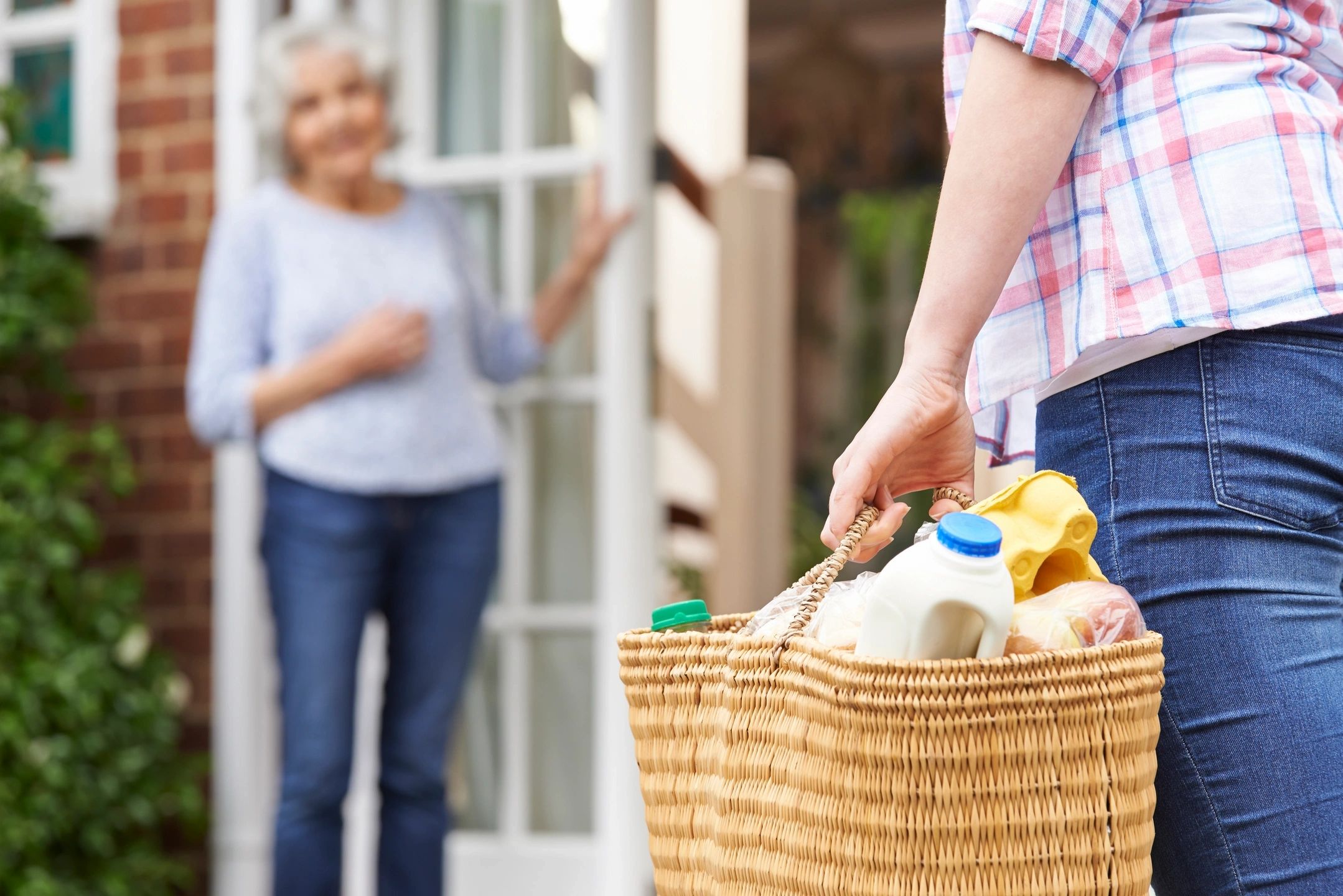 Older person at a door in Philadelphia waiting for an aide carrying groceries