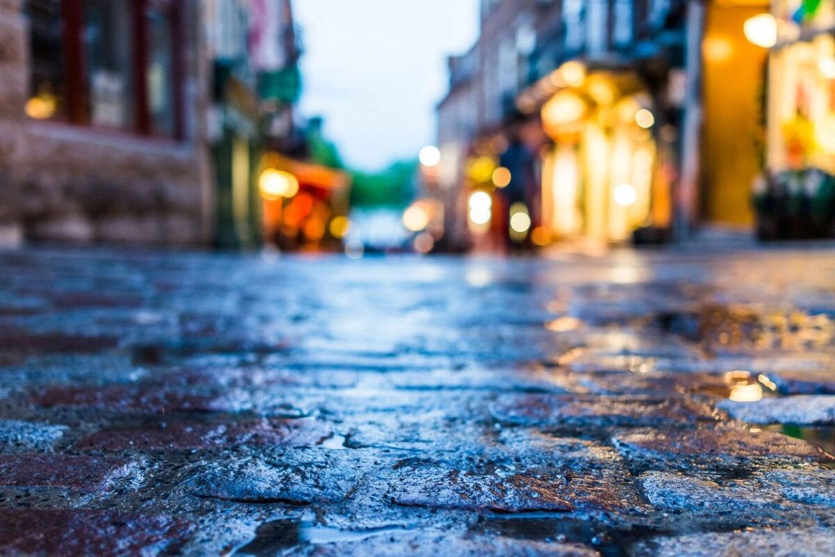 Dusk city scene with a view from a stone street with lights coming from windows
